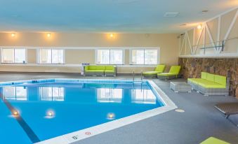 a large indoor swimming pool surrounded by lounge chairs , where people are relaxing and enjoying their time at Rodeway Inn