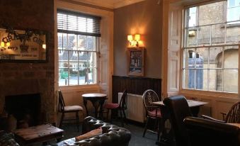 a cozy restaurant with wooden furniture , large windows , and a dining table set for a meal at The White Hart Hotel