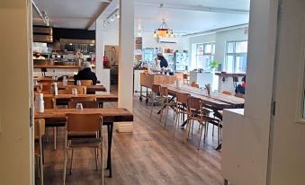 a large , open dining room with wooden floors and tables set for a meal , as well as a person sitting at one of the tables at Hotel du Nord