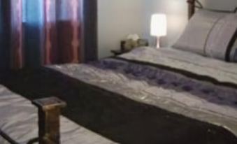a cozy bedroom with a large bed , a lamp , and a potted plant on the floor at Number Twelve