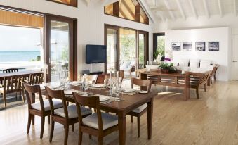a spacious living room with wooden furniture , including a dining table , chairs , and a couch at Como Parrot Cay