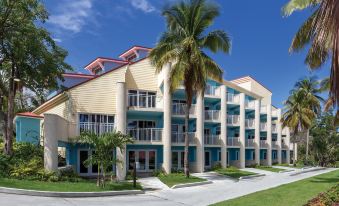 a large building with a blue and white facade is surrounded by palm trees and grass at Margaritaville Vacation Club by Wyndham - St Thomas