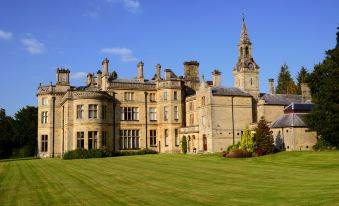 a large stone building with a grassy lawn and a tall steeple in the background at Pale Hall Hotel