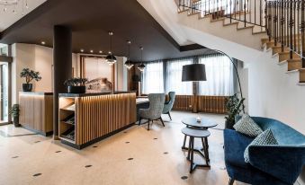 a modern hotel lobby with a wooden reception desk , comfortable seating , and a large window at Hotel Post Alpine Cityflair