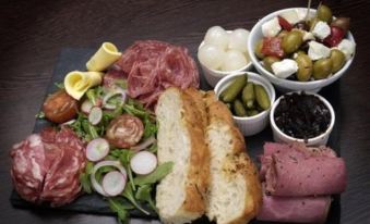 a platter filled with an assortment of meats , cheeses , olives , and bread , creating a delicious meal at The George at Nunney