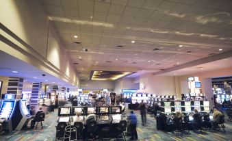 a large room filled with various gaming machines , including joysticks and monitors , as well as people playing games at Jackpot Junction Casino Hotel