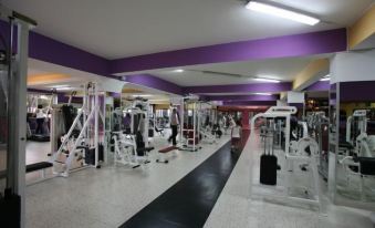 a large , well - lit gym with various exercise equipment , including treadmills , weight machines , and a black and white flooring at Hotel All'Antico Pozzo
