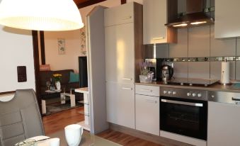 a modern kitchen with white cabinets , a dining table , and a living room in the background at Scout