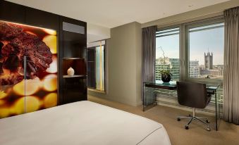 a hotel room with a king - sized bed , a desk , and a window overlooking the city at Park Plaza Westminster Bridge London