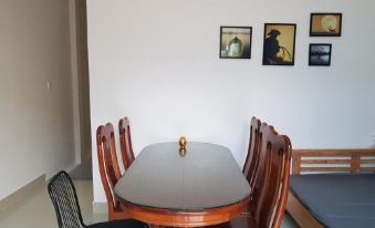 a wooden dining table with chairs and a gold vase in the center , surrounded by three paintings on the wall at Sen Villa Boutique