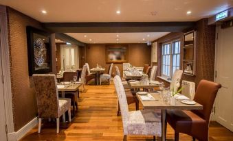 a large dining room with wooden floors , tables , and chairs arranged for a group of people at Victoria Hotel