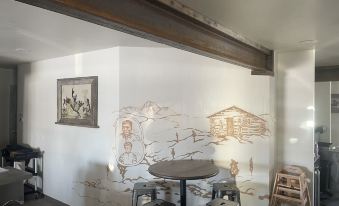 a small dining room with a round table , chairs , and a mural on the wall at Challis Roadhouse