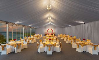 a large banquet hall with multiple tables set for a formal event , including gold and white tableware at DoubleTree by Hilton Goa - Panaji