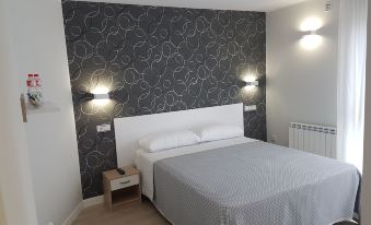a modern bedroom with a white bed , gray and white bedding , and two wall - mounted lamps at Los Rosales