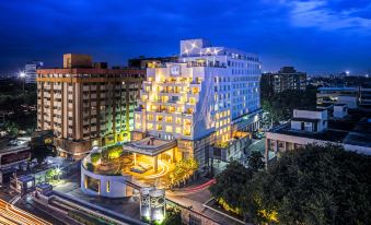 a large white building with a curved roof is surrounded by other buildings and trees at night at The Park Chennai