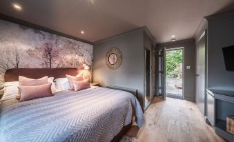 a cozy bedroom with a large bed , hardwood floors , and a door leading to a patio at The Cricketers Clavering