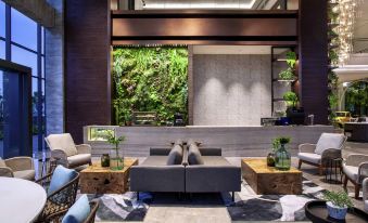 a modern hotel lobby with a couch , chairs , and potted plants in the background at Mercure Tangerang BSD City