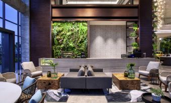 a modern living room with a couch , chairs , and wooden tables in front of a large window at Mercure Tangerang BSD City