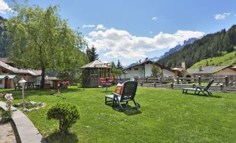 a lush green lawn with several chairs and benches placed in the middle , surrounded by mountains at Cecilia