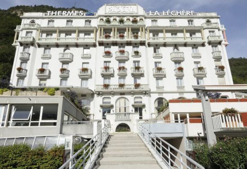 "a large white building with the name "" thermes la lechère "" on it , located in a city with many bridges and stairs leading" at Hotel & Spa Radiana