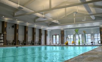 an indoor swimming pool with a large ceiling , surrounded by chairs and umbrellas , under a high ceiling with exposed pipes at Hilton Myrtle Beach Resort