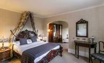 a large bed with a wooden headboard and footboard is in a room with a mirror , table , and sink at Dalhousie Castle Hotel