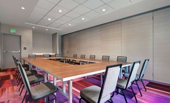 a conference room with a long wooden table , chairs , and a large screen on the wall at Home2 Suites by Hilton Tracy