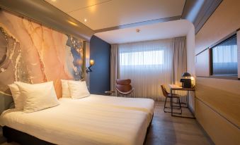 a hotel room with a large bed , a desk , and a chair in the corner at Leonardo Hotel Almere City Center