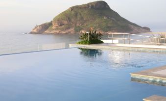 a large swimming pool with a plant in the foreground and an island in the background at CDesign Hotel