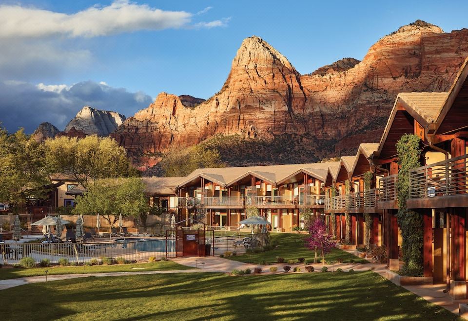 a resort with wooden cabins and a pool , surrounded by lush greenery and mountains in the background at Desert Pearl Inn