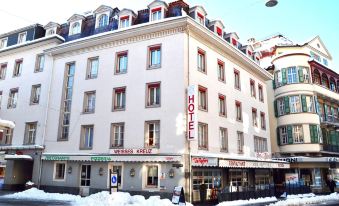 "a large white building with a sign that says "" hotel "" and snow on the ground" at Hotel Weisses Kreuz