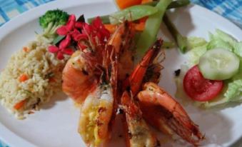 a white plate with a variety of food items , including shrimp , rice , and vegetables , placed on a dining table at Hotel Miraflores