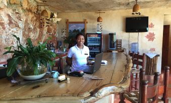 a woman sitting at a wooden bar with a laptop in front of her , smiling and greeting customers at Altos de Cano Hondo