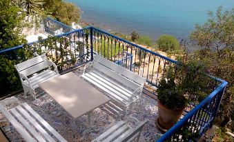 a balcony overlooking a body of water , with a dining table and chairs placed on the balcony at La Villa Bleue