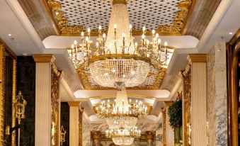 A large chandelier hangs from the ceiling in an ornate room with mirrored walls at Hotel Alexandra