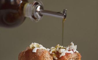 a person is pouring olive oil onto two slices of bread topped with cheese and nuts at Sofia Hotel