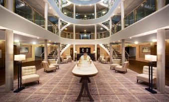 a large , modern hotel lobby with multiple floors , multiple seating areas , and a grand staircase at Leonardo Hotel and Conference Venue Hinckley Island