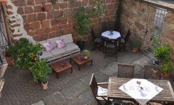 an outdoor patio with a dining table , chairs , and a couch surrounded by potted plants at LUDWIGS