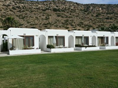 a row of white houses with potted plants in front of them , situated on a grassy field at Valley Village