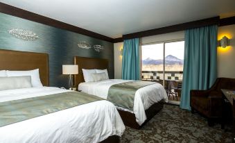 a hotel room with two beds , a window offering a view of mountains , and lamps on the bedside tables at Ute Mountain Casino Hotel