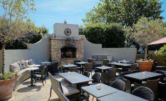 an outdoor dining area with tables and chairs arranged in a courtyard , surrounded by a stone wall at Horse & Hound