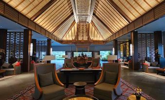 a spacious lobby with high ceilings , wooden beams , and a large table surrounded by chairs at The Singhasari Resort Batu