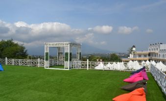 a green lawn with a white pergola and several colorful bean bag chairs in the foreground at Chevilly Resort & Camp