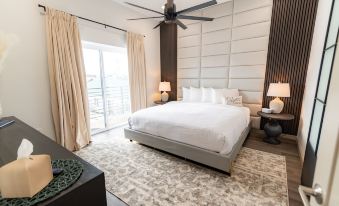 a spacious bedroom with a large bed , white walls , and a door leading to a balcony at Colony Suites