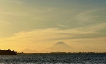 a serene sunset over a calm body of water , with a mountain in the background at Rinjani Beach Eco Resort