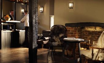 a dimly lit room with a chair , table , and fireplace , as well as a woman in the background at The Crown
