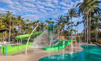 a water park with a large pool , slides , and palm trees under a blue sky at Discovery Parks - Rockhampton