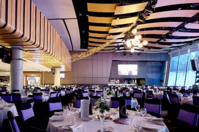 a large banquet hall with multiple tables and chairs , some of which are set up for an event at Oval Hotel at Adelaide Oval, an EVT hotel