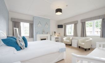 a large bedroom with a white bed , a fireplace , and two chairs arranged around the room at The Fishbourne