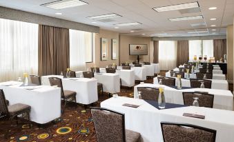 a conference room with multiple tables and chairs arranged for a meeting or event , providing a well - organized and comfortable atmosphere at Hilton Los Angeles-Culver City, CA